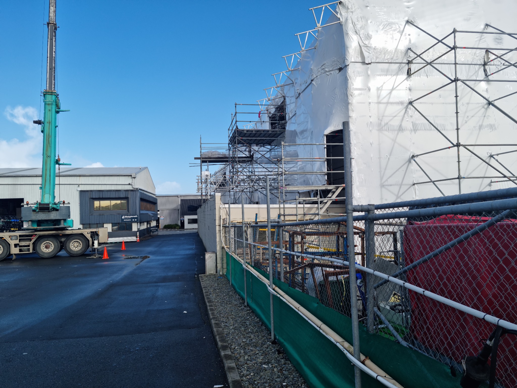 Fully wrapped Wiri warehouse with scaffolding and crane during the controlled reroof